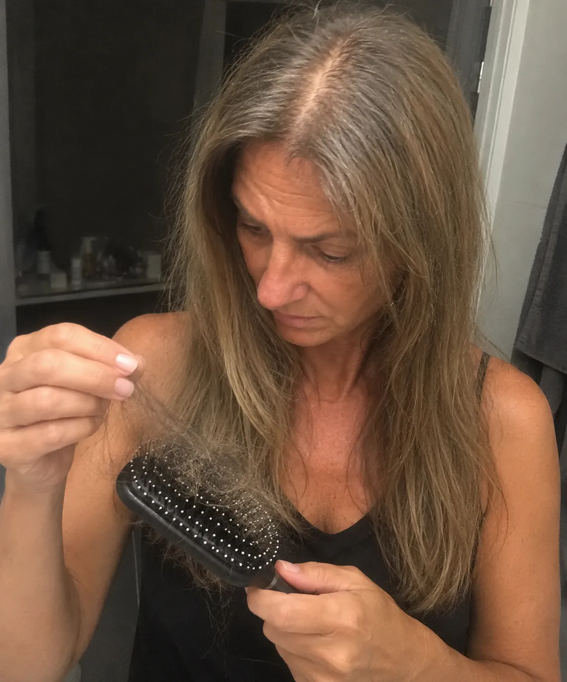 Woman looking at hair collected in her hairbrush